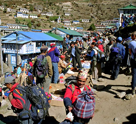 A crowded outdoor market in the mountains of Nepal with vendors and buyers exchanging goods directly