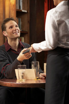 A customer in a café handing cash to a server — an everyday free-market exchange