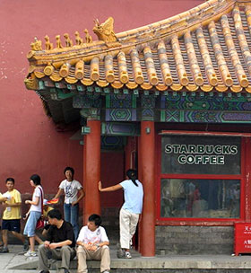 A Starbucks storefront tucked beneath traditional ornate red-and-gold Chinese temple roof architecture